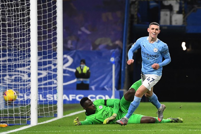 LONDON, ENGLAND - JANUARY 03: Phil Foden of Manchester City celebrates after scoring their sides second goal as Edouard Mendy of Chelsea looks dejected during the Premier League match between Chelsea and Manchester City at Stamford Bridge on January 03, 2021 in London, England. The match will be played without fans, behind closed doors as a Covid-19 precaution. (Photo by Andy Rain - Pool/Getty Images)