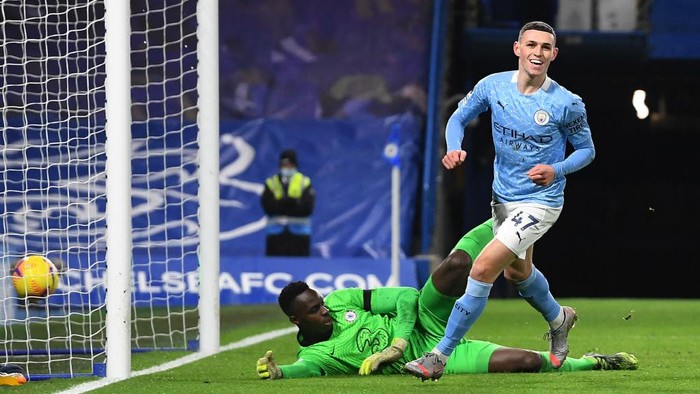 LONDON, ENGLAND - JANUARY 03: Phil Foden of Manchester City celebrates after scoring their sides second goal as Edouard Mendy of Chelsea looks dejected during the Premier League match between Chelsea and Manchester City at Stamford Bridge on January 03, 2021 in London, England. The match will be played without fans, behind closed doors as a Covid-19 precaution. (Photo by Andy Rain - Pool/Getty Images)