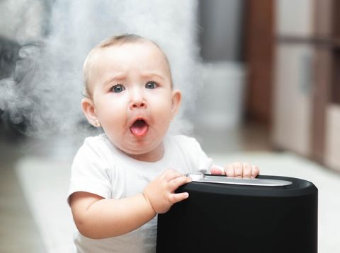 The baby looks at the humidifier. Moisture in the home healthy air concept