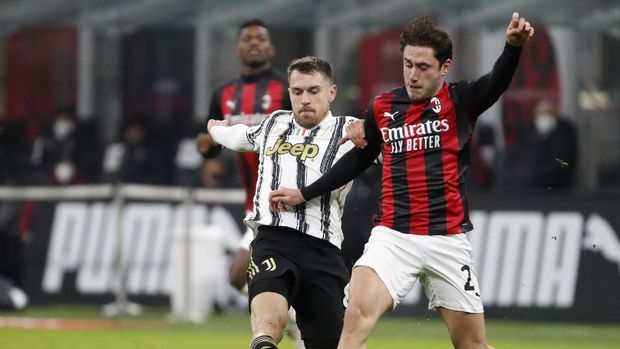 Juventus' Aaron Ramsey, left, duels for the ball with AC Milan's Davide Calabria during the Serie A soccer match between AC Milan and Juventus at the San Siro stadium, in Milan, Italy, Wednesday, Jan. 6, 2021. (AP Photo/Antonio Calanni)