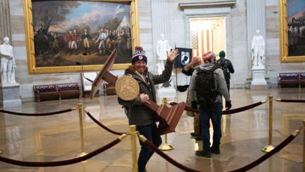 WASHINGTON, DC - JANUARY 06: A pro-Trump protester carries the lectern of U.S. Speaker of the House Nancy Pelosi through the Roturnda of the U.S. Capitol Building after a pro-Trump mob stormed the building on January 06, 2021 in Washington, DC. Congress held a joint session today to ratify President-elect Joe Biden's 306-232 Electoral College win over President Donald Trump. A group of Republican senators said they would reject the Electoral College votes of several states unless Congress appointed a commission to audit the election results.   Win McNamee/Getty Images/AFP