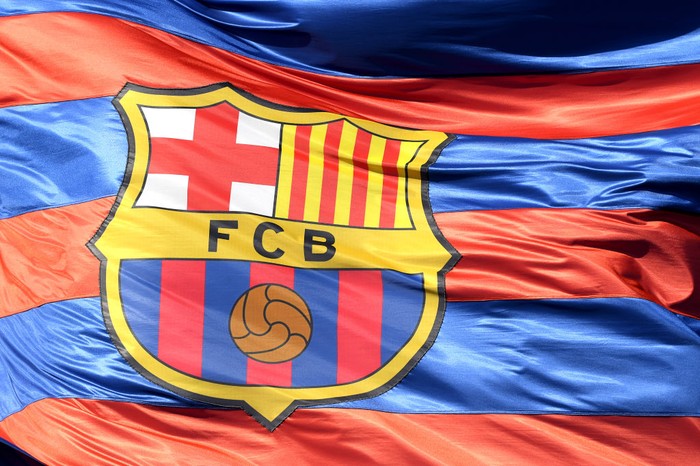 Barcelona, Logo Barcelona, Bendera Barcelona BARCELONA, SPAIN - APRIL 04: The Barcelona logo is seen on a flag waving above the stadium prior to the UEFA Champions League Quarter Final Leg One match between FC Barcelona and AS Roma at Camp Nou on April 4, 2018 in Barcelona, Spain. (Photo by Mike Hewitt/Getty Images)