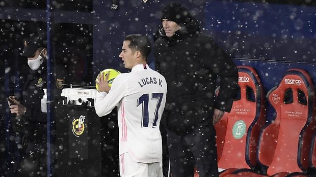 Real Madrid's head coach Zinedine Zidane, right, watches as Real Madrid's Lucas Vazquez prepares to take a throw-in during a Spanish La Liga soccer match between Osasuna and Real Madrid at El Sadar stadium in Pamplona, Spain, Saturday, Jan. 9, 2021. (AP Photo/Alvaro Barrientos)