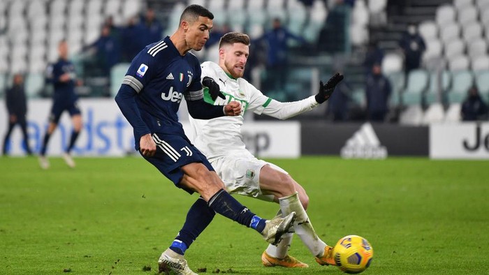 TURIN, ITALY - JANUARY 10: Cristiano Ronaldo of Juventus F.C.  scores their teams third goal under pressure from Georgios Kyriakopoulos of Sassuolo during the Serie A match between Juventus and US Sassuolo at Allianz Stadium on January 10, 2021 in Turin, Italy. Sporting stadiums around Italy remain under strict restrictions due to the Coronavirus Pandemic as Government social distancing laws prohibit fans inside venues resulting in games being played behind closed doors. (Photo by Valerio Pennicino/Getty Images )