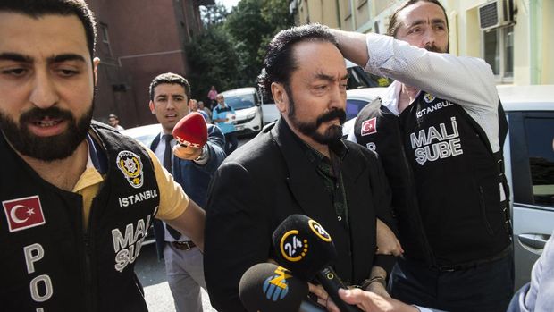 Turkish police officers escort televangelist and leader of a sect, Adnan Oktar (C) on July 11, 2018, in Istanbul, as he is arrested on fraud charges. - Turkish police detained the televangelist on fraud charges on July 11, 2018, notorious for propagating conservative views while surrounded by scantily-clad women he refers to as his 