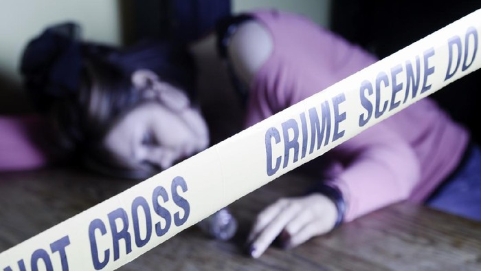 A dead body laying on the floor behind crime scene tape in a darkened room with muted color.