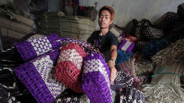 Seorang pekerja menyelesaikan pembuatan kerajinan tas berbahan daun pandan di Rajapolah, Tasikmalaya, Jawa Barat, Sabtu 1312. Pemprov Jawa Barat mendorong produk unggulan daerah untuk menghadapi MEA 2015 dengan  mengoptimaklan infrastruktur dan kemudahan
