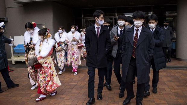 Twenty-year-old men and women dressed in kimonos and suits leave Todoroki Arena during the 