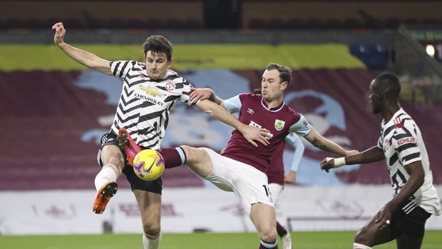 Manchester United's Harry Maguire, left, fights for the ball with Burnley's Ashley Barnes, right, during the English Premier League soccer match between Burnley and Manchester United in Burnley, England, Tuesday, Jan. 12, 2021. (Clive Brunskill/Pool via AP)