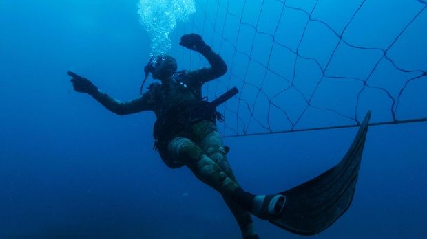 Shark activist Walter Bernardis swims along a shark net during a dive in Umkomaas near Durban, South Africa, on December 10, 2020. - Today, on more than 300km of KwaZulu-Natal coast, 37 beaches are equipped with a controversial shark control system, made of shark nets -  two parallel rows of submerged mesh net - and drum lines - an aquatic trap used to lure and capture large sharks using baited hooks - both placed around beaches to reduce shark attacks on swimmers. Although there has not been any mortal attack for 67 years, every year at least 400 sharks have been killed by this system, prompting environmentalists to criticise it for its ecological danger. (Photo by Michele Spatari / AFP)