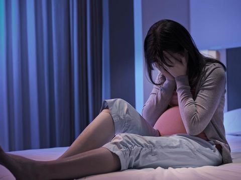 pregnant woman sit on the bed and feel depression at home