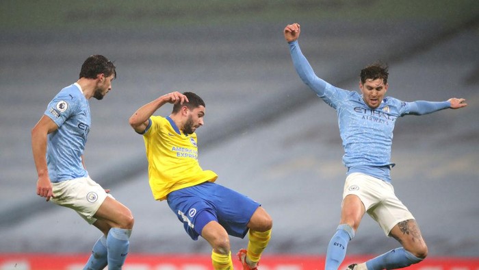 MANCHESTER, ENGLAND - JANUARY 13: Neal Maupay of Brighton and Hove Albion shoots under pressure from Ruben Dias and John Stones of Manchester City during the Premier League match between Manchester City and Brighton & Hove Albion at Etihad Stadium on January 13, 2021 in Manchester, England. Sporting stadiums around England remain under strict restrictions due to the Coronavirus Pandemic as Government social distancing laws prohibit fans inside venues resulting in games being played behind closed doors. (Photo by Clive Brunskill/Getty Images)