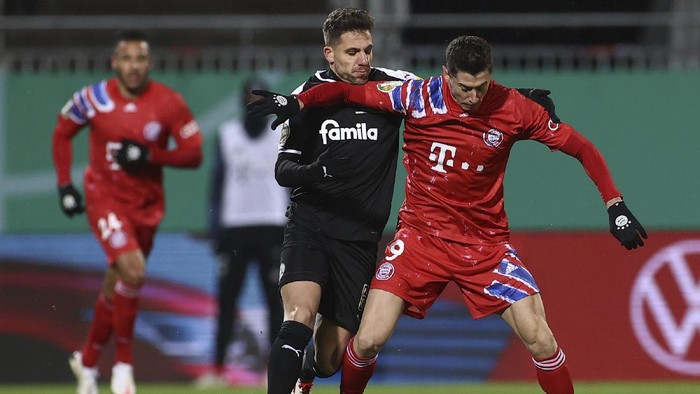 Kiels Ahmet Arslan and Munichs Robert Lewandowski, right, in action during the DFB Cup 2nd round match between Holstein Kiel and Bayern Munich at the Holstein Stadium in Kiel, Wednesday Jan. 13, 2021. (Christian Charisius/dpa via AP)