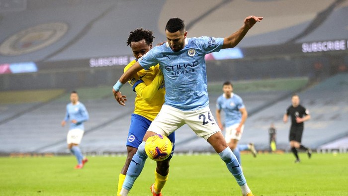 MANCHESTER, ENGLAND - JANUARY 13: Riyad Mahrez of Manchester City battles for possession with Percy Tau of Brighton and Hove Albion during the Premier League match between Manchester City and Brighton & Hove Albion at Etihad Stadium on January 13, 2021 in Manchester, England. Sporting stadiums around England remain under strict restrictions due to the Coronavirus Pandemic as Government social distancing laws prohibit fans inside venues resulting in games being played behind closed doors. (Photo by Clive Brunskill/Getty Images)