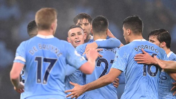 MANCHESTER, ENGLAND - JANUARY 13: Phil Foden of Manchester City is congratulated by teammates John Stones and Joao Cancelo after scoring their team's first goal during the Premier League match between Manchester City and Brighton & Hove Albion at Etihad Stadium on January 13, 2021 in Manchester, England. Sporting stadiums around England remain under strict restrictions due to the Coronavirus Pandemic as Government social distancing laws prohibit fans inside venues resulting in games being played behind closed doors. (Photo by Laurence Griffiths/Getty Images)
