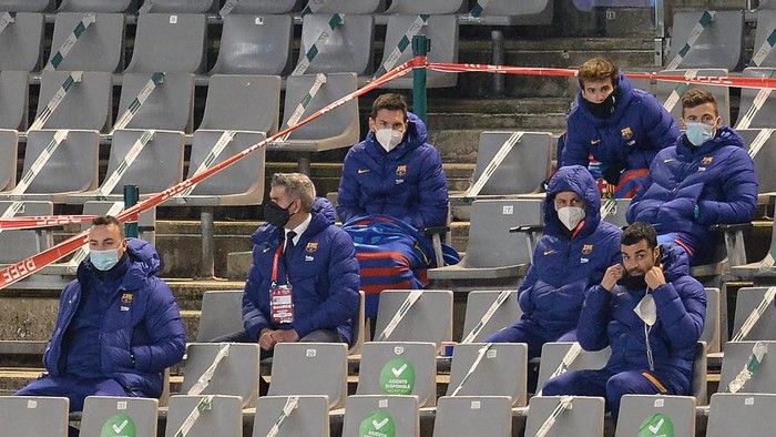Barcelonas Argentinian forward Lionel Messi (C) sits with substitutes on the grandstands during the Spanish Super Cup semi final football match between Real Sociedad and FC Barcelona at the Nuevo Arcangel stadium in Cordoba on January 13, 2021. - Lionel Messi was left out of Barcelonas Spanish Super Cup semi-final against Real Sociedad today due to injury. (Photo by CRISTINA QUICLER / AFP)