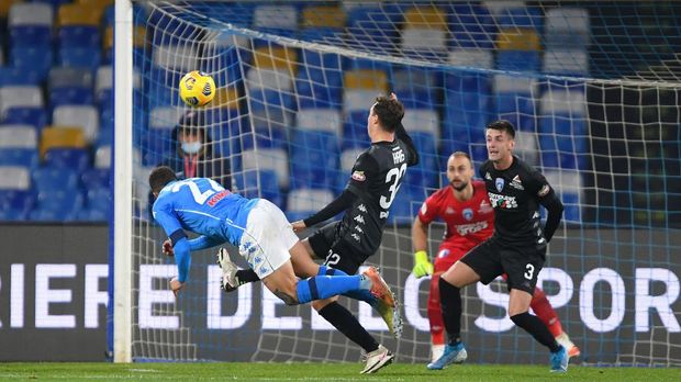 NAPLES, ITALY - JANUARY 13: Giovanni Di Lorenzo of Napoli scores their team's first goal as Nicolas Haas of Empoli attempts to block during the Coppa Italia match between SSC Napoli and Empoli FC at Stadio Diego Armando Maradona on January 13, 2021 in Naples, Italy. Sporting stadiums around Italy remain under strict restrictions due to the Coronavirus Pandemic as Government social distancing laws prohibit fans inside venues resulting in games being played behind closed doors. (Photo by Francesco Pecoraro/Getty Images)