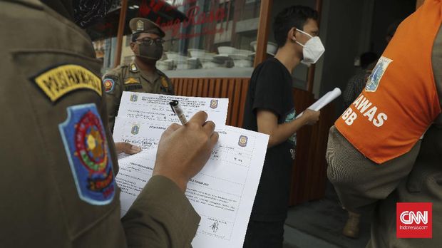 Sejumlah petugas Satpol PP Kecamatan Cilandak melakukan inspeksi protkes PPKM di sejumlah tempat makan di kawasan Fatmawati, Jaksel, Kamis, 14 Januari 2020. Bagi tempat makan yang melanggar protkes PPKM petugas memberikan teguran tertulis yang ditempelkan di depan toko/tempat makan pemilik. CNNIndonesia/Safir Makki