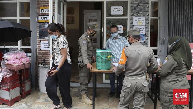 Sejumlah petugas Satpol PP Kecamatan Cilandak melakukan inspeksi protkes PPKM di sejumlah tempat makan di kawasan Fatmawati, Jaksel, Kamis, 14 Januari 2020. Bagi tempat makan yang melanggar protkes PPKM petugas memberikan teguran tertulis yang ditempelkan di depan toko/tempat makan pemilik. CNNIndonesia/Safir Makki