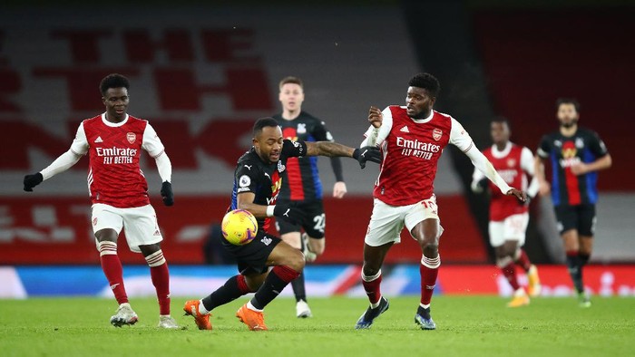 LONDON, ENGLAND - JANUARY 14: Thomas Partey of Arsenal battles for possession with Jordan Ayew of Crystal Palace  during the Premier League match between Arsenal and Crystal Palace at Emirates Stadium on January 14, 2021 in London, England. Sporting stadiums around England remain under strict restrictions due to the Coronavirus Pandemic as Government social distancing laws prohibit fans inside venues resulting in games being played behind closed doors. (Photo by Julian Finney/Getty Images)