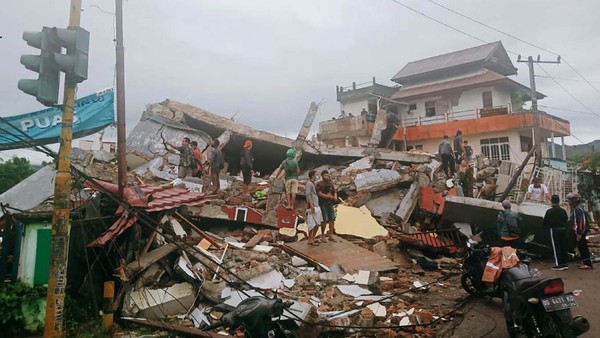 Residents inspect earthquake-damaged buildings in Mamuju, West Sulawesi, Indonesia, Friday, Jan. 15, 2021. A strong inland and shallow earthquake hit eastern Indonesia early Friday causing people to panic in parts of the countrys Sulawesi island and run to higher ground. (AP Photo/Rudy Akdyaksyah)