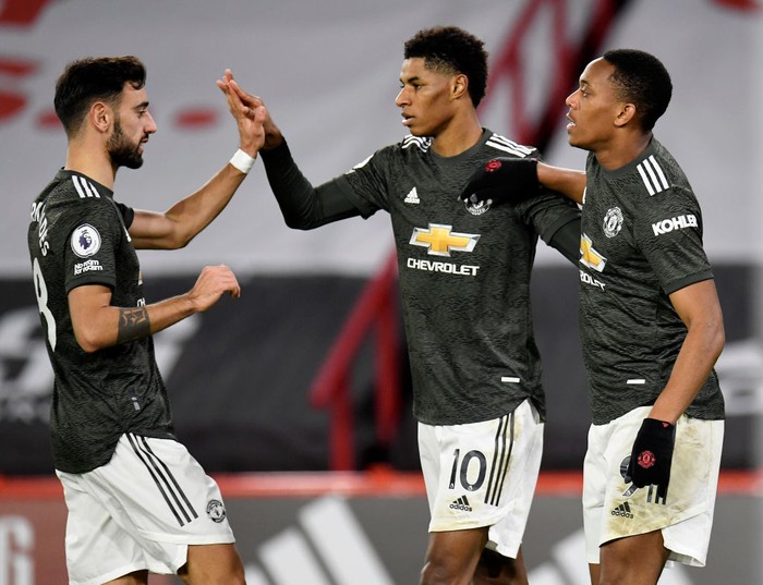 SHEFFIELD, ENGLAND - DECEMBER 17: Marcus Rashford of Manchester United celebrates with team mates (l - r) Bruno Fernandes and Anthony Martial after scoring their sides third goal  during the Premier League match between Sheffield United and Manchester United at Bramall Lane on December 17, 2020 in Sheffield, England. The match will be played without fans, behind closed doors as a Covid-19 precaution.  (Photo by Peter Powell - Pool/Getty Images)
