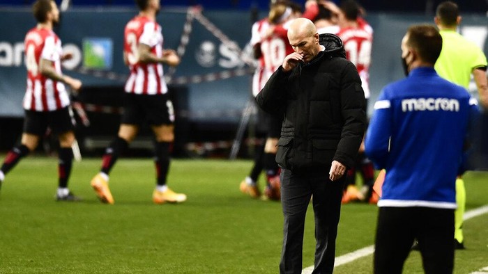Real Madrids head coach Zinedine Zidane gestures as Athletic Bilbao players, background, celebrate their first goal during Spanish Super Cup semi final soccer match between Real Madrid and Athletic Bilbao at La Rosaleda stadium in Malaga, Spain, Thursday, Jan. 14, 2021. (AP Photo/Jose Breton)