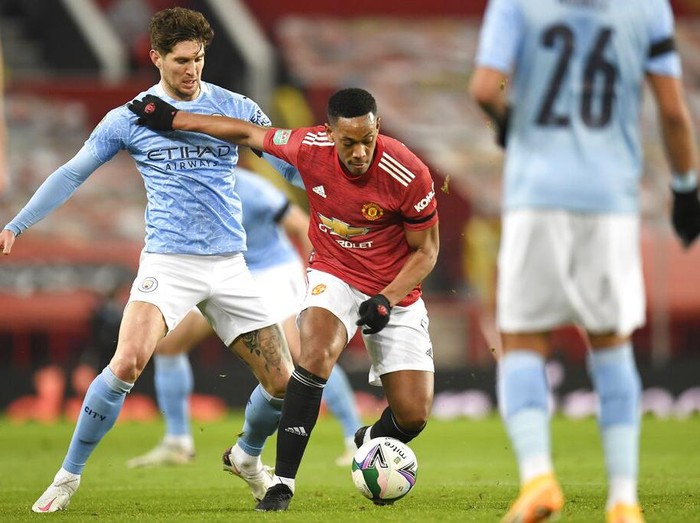 Manchester Citys John Stones, left, and Manchester Uniteds Anthony Martial fight for the ball during the English League Cup semifinal soccer match between Manchester United and Manchester City at Old Trafford in Manchester, England, Wednesday, Jan. 6, 2021. (Peter Powell/Pool via AP)