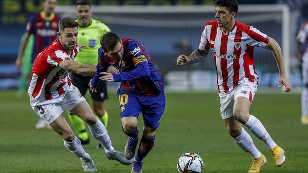 Barcelona's Lionel Messi, center, runs past Athletic Bilbao's Ander Capa, right, and Athletic Bilbao's Yeray Alvarez during the Spanish Supercopa final soccer match between FC Barcelona and Athletic Bilbao at La Cartuja stadium in Seville, Spain, Sunday, Jan. 17, 2021. (AP Photo/Miguel Morenatti)