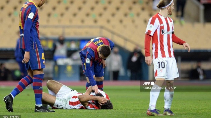 Barcelonas Argentinian forward Lionel Messi checks on Athletic Bilbaos Spanish forward Asier Villalibre (BOTTOM) during the Spanish Super Cup final football match between FC Barcelona and Athletic Club Bilbao at La Cartuja stadium in Seville on January 17, 2021. (Photo by CRISTINA QUICLER / AFP)