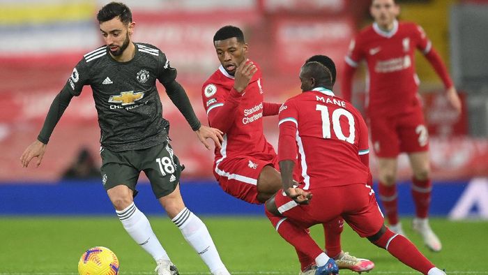 Liverpool vs Manchester United LIVERPOOL, ENGLAND - JANUARY 17: (L - R) Bruno Fernandes of Manchester United is challenged by Georginio Wijnaldum and Sadio Mane of Liverpool during the Premier League match between Liverpool and Manchester United at Anfield on January 17, 2021 in Liverpool, England. Sporting stadiums around England remain under strict restrictions due to the Coronavirus Pandemic as Government social distancing laws prohibit fans inside venues resulting in games being played behind closed doors. (Photo by Michael Regan/Getty Images)