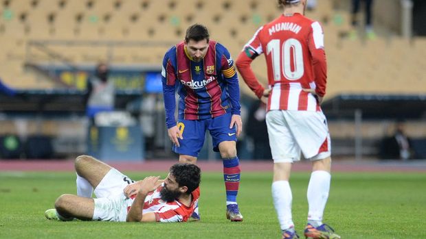 Barcelona's Argentinian forward Lionel Messi checks on Athletic Bilbao's Spanish forward Asier Villalibre (BOTTOM) during the Spanish Super Cup final football match between FC Barcelona and Athletic Club Bilbao at La Cartuja stadium in Seville on January 17, 2021. (Photo by CRISTINA QUICLER / AFP)