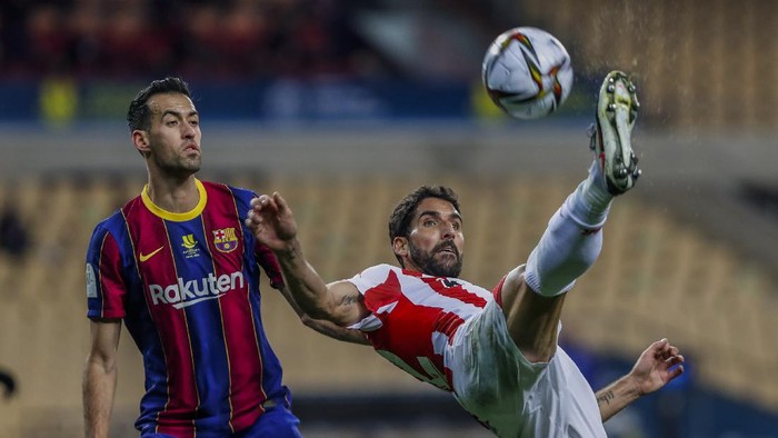 Athletic Bilbaos Raul Garcia, right, kicks the ball next to Barcelonas Sergio Busquets with during the Spanish Supercopa final soccer match between FC Barcelona and Athletic Bilbao at La Cartuja stadium in Seville, Spain, Sunday, Jan. 17, 2021. (AP Photo/Miguel Morenatti)