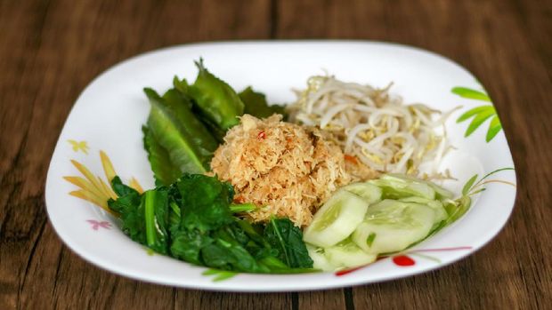 Sayur urap on wood background. Cooked vegetables with spiced grated coconut. Indonesian traditional food.