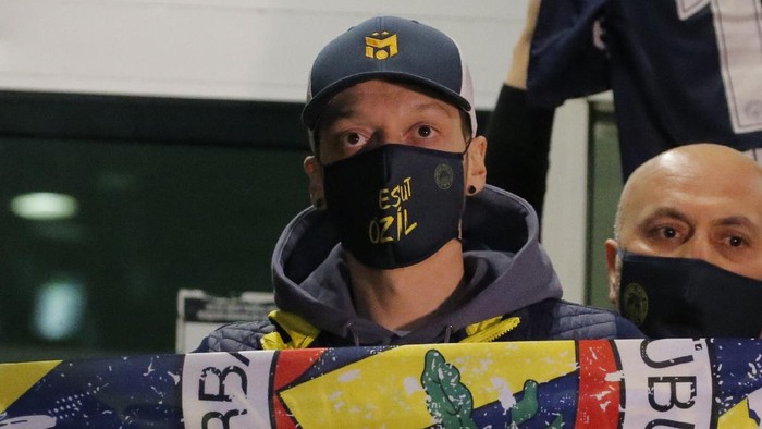 Mesut Ozil, former Germany midfielder poses for the photographers with a Fenerbahce scarf after arriving at the Ataturk Airport in Istanbul, early Monday, Jan. 18, 2021. Ozil, who is of Turkish descent, will look to reignite his career in Turkey after he left Arsenal to join Fenerbahce. (AP Photo)