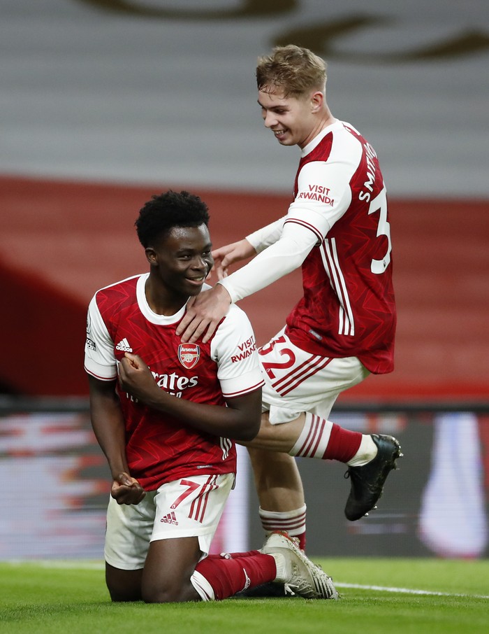 Arsenal LONDON, ENGLAND - DECEMBER 26: Bukayo Saka of Arsenal celebrates with teammates Emile Smith Rowe after scoring his team's third goal during the Premier League match between Arsenal and Chelsea at Emirates Stadium on December 26, 2020 in London, England. The match will be played without fans, behind closed doors as a Covid-19 precaution. (Photo by Andrew Boyers - Pool/Getty Images)