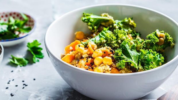 Vegan stew with chickpeas, sweet potato and kale in a white bowl.