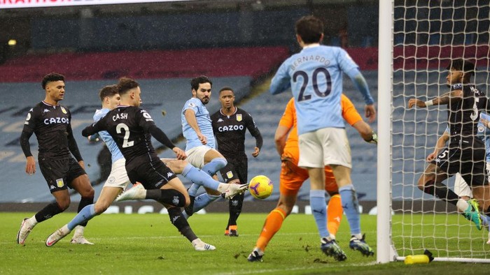 MANCHESTER, ENGLAND - JANUARY 20: Ilkay Gundogan and John Stones of Manchester City stretch to shoot towards goal as Matty Cash of Aston Villa challenges during the Premier League match between Manchester City and Aston Villa at Etihad Stadium on January 20, 2021 in Manchester, England. Sporting stadiums around the UK remain under strict restrictions due to the Coronavirus Pandemic as Government social distancing laws prohibit fans inside venues resulting in games being played behind closed doors. (Photo by Clive Brunskill/Getty Images)