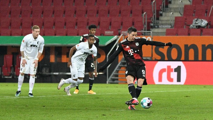 AUGSBURG, GERMANY - JANUARY 20: Robert Lewandowski of Bayern Munich scores their teams first goal from the penalty spot  during the Bundesliga match between FC Augsburg and FC Bayern Muenchen at WWK-Arena on January 20, 2021 in Augsburg, Germany. Sporting stadiums around Germany remain under strict restrictions due to the Coronavirus Pandemic as Government social distancing laws prohibit fans inside venues resulting in games being played behind closed doors. (Photo by Philipp Guelland - Pool/Getty Images)