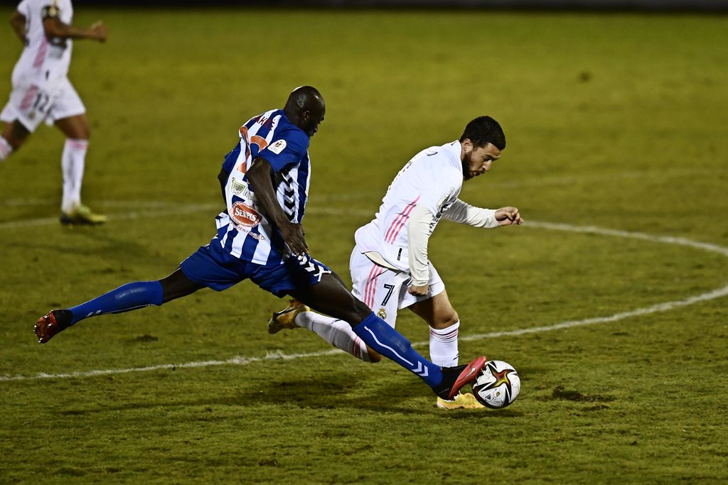 Alcoyano's Ali Diakite, left, challenges for the ball with Real Madrid's Eden Hazard during a Spanish Copa del Rey round of 32 soccer match between Alcoyano and Real Madrid at the El Collao stadium in Alcoy, Spain, Wednesday Jan. 20, 2021. (AP Photo/Jose Breton)