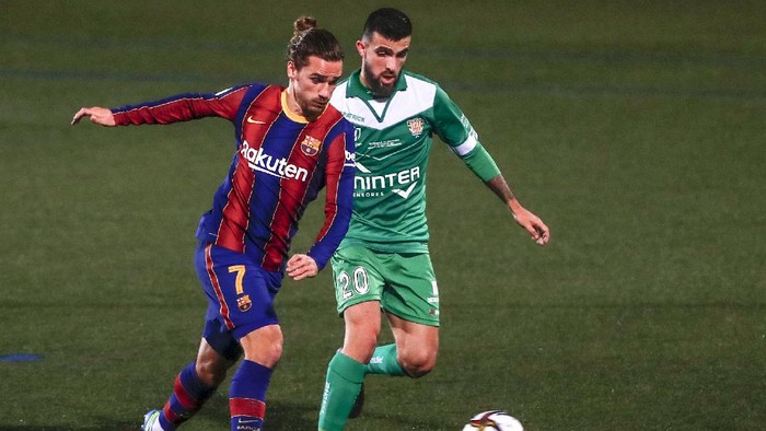 Barcelonas Antoine Griezmann, left, vies for the ball with Cornellas Agus Medina during a Spanish Copa del Rey round of 32 soccer match between Cornella and FC Barcelona at the Nou Municipal stadium in Cornella, Spain, Thursday, Jan. 21, 2021. (AP Photo/Joan Monfort)