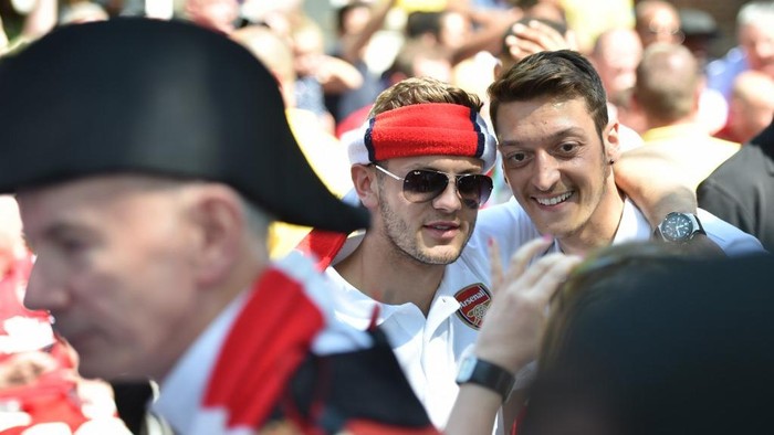 Arsenals English midfielder Jack Wilshere (C) and Arsenals German midfielder Mesut Ozil pose for photographs during their victory parade in London on May 18, 2014, following their win in the English FA Cup final football match on May 17, 2014 against Hull City.  Aaron Ramsey insists Arsenals dramatic FA Cup final victory will be the springboard for more glory now the Gunners have finally ended their trophy drought. Ramsey scored the extra-time goal that clinched a 3-2 win over Hull in Saturdays clash at Wembley, putting silverware back in the Arsenal trophy cabinet for the first time since 2005.  AFP PHOTO /  LEON NEAL (Photo by LEON NEAL / AFP)