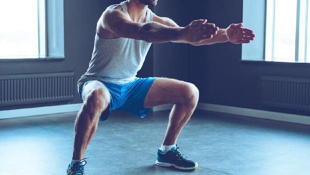 Part of young man in sportswear doing squat at gym