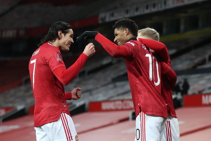 MANCHESTER, ENGLAND - JANUARY 24: Marcus Rashford of Manchester United is congratulated by team mates (L - R) Edinson Cavani and Donny Van De Beek after scoring their sides second goal during The Emirates FA Cup Fourth Round match between Manchester United and Liverpool at Old Trafford on January 24, 2021 in Manchester, England. Sporting stadiums around the UK remain under strict restrictions due to the Coronavirus Pandemic as Government social distancing laws prohibit fans inside venues resulting in games being played behind closed doors. (Photo by Martin Rickett - Pool/Getty Images)