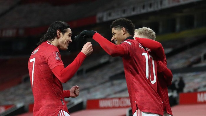 MANCHESTER, ENGLAND - JANUARY 24: Marcus Rashford of Manchester United is congratulated by team mates (L - R) Edinson Cavani and Donny Van De Beek after scoring their sides second goal during The Emirates FA Cup Fourth Round match between Manchester United and Liverpool at Old Trafford on January 24, 2021 in Manchester, England. Sporting stadiums around the UK remain under strict restrictions due to the Coronavirus Pandemic as Government social distancing laws prohibit fans inside venues resulting in games being played behind closed doors. (Photo by Martin Rickett - Pool/Getty Images)