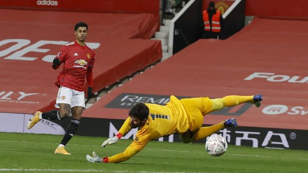 Manchester United's Marcus Rashford scores his sides second goal of the game past a diving Liverpool's goalkeeper Alisson during the English FA Cup 4th round soccer match between Manchester United and Liverpool at Old Trafford in Manchester, England, Sunday, Jan. 24, 2021. (Phil Noble/Pool via AP)