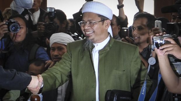 Indonesian Islamic militant Mohammed Jibril Abdurahman (L) shakes the hand of his father, Abu Jibril (R) as he attends his trial at South Jakarta court on February 23, 2010. Jibril went on trial accused of helping to finance deadly attacks on luxury hotels in Jakarta last year, charges that risk up to 15 years in jail. The July bombings killed seven people as well as two suicide bombers and marked the bloody end of a four-year hiatus in attacks attributed to late terror leader Noordin Mohammad Top and Al-Qaeda-linked regional network Jemaah Islamiyah. AFP PHOTO / Bay ISMOYO (Photo by BAY ISMOYO / AFP)