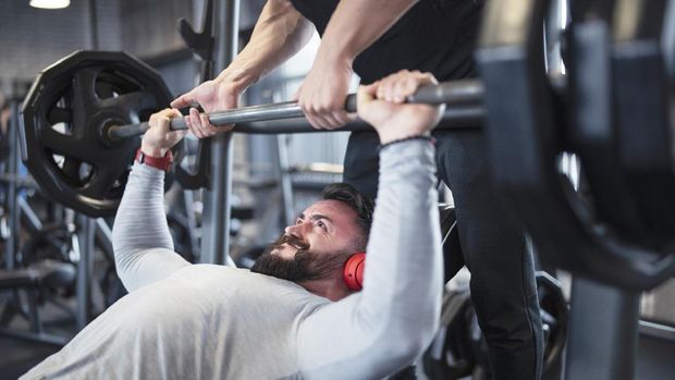 Two friends exercising bench press in gym