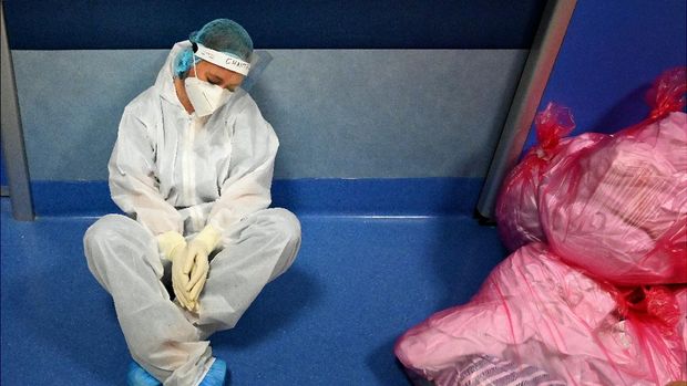 A medical worker in personal protective equipment (PPE) sits on the floor resting at the COVID 3 level Intensive Care Unit (ICU) for novel coronavirus, COVID-19 cases, at the Casal Palocco hospital, near Rome on October 22, 2020. (Photo by Alberto PIZZOLI / AFP)