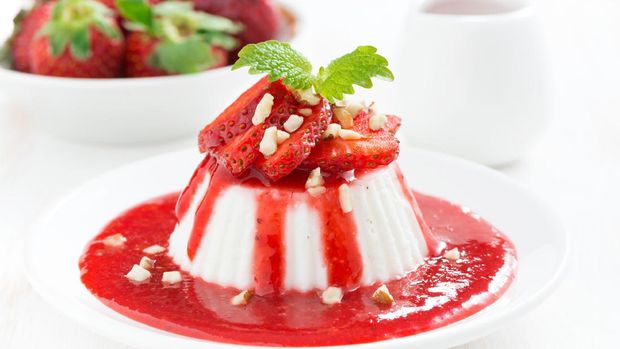 Vanilla panna cotta with strawberry sauce on a plate, close-up
